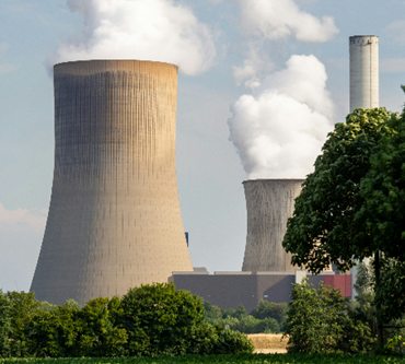 two chimneys of a nuclear power plant with smoke billowing from them 